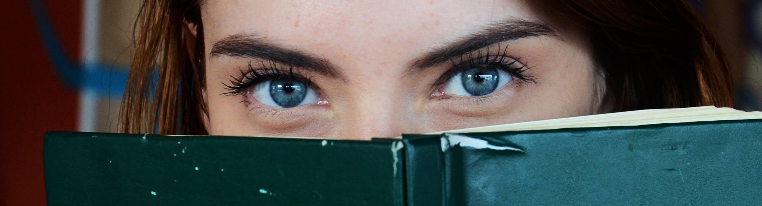 big blue eyes looking behind a book
